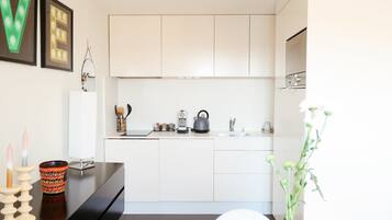 A modern kitchen with white cabinets, a black countertop, and a sink. There are decorative items like candles and a vase with flowers on the counter.
