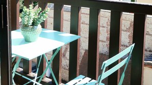 Ein Balkon mit Tisch und Stühlen, einem Blumentopf und Blick auf Wohnhäuser.