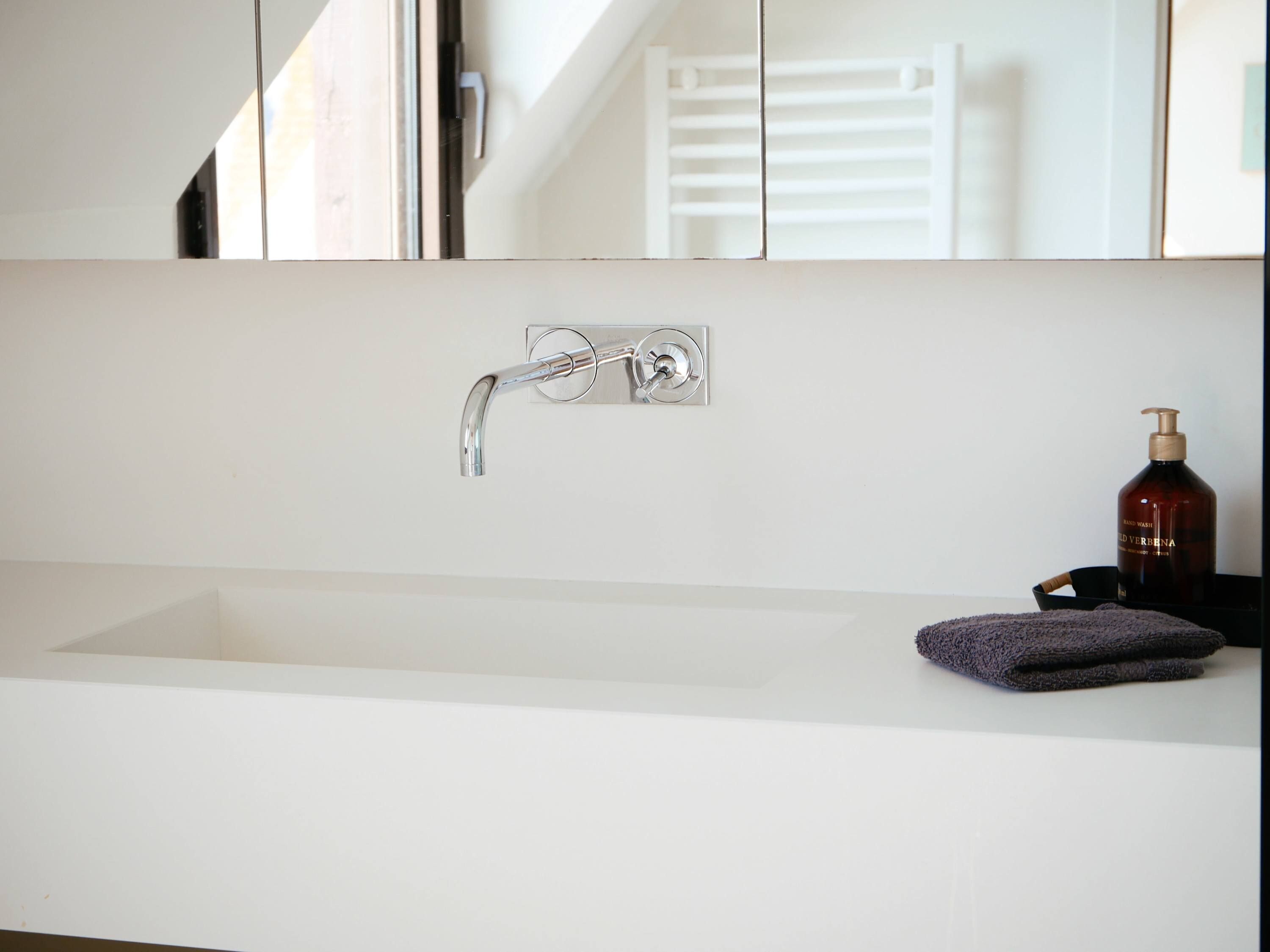 Une salle de bain avec un lavabo blanc, un robinet chromé et un flacon de savon pour les mains.