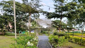 A pathway lined with gravel and bordered by greenery, leading to a covered structure.