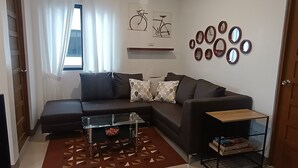 A modern living room with a sectional sofa, a coffee table, a patterned rug, and a wall with circular mirrors.