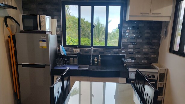 A modern kitchen with a refrigerator, microwave, stove, and a window with a view of greenery.