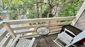 Un espace extérieur abrité comprenant un banc en bois, une petite table ronde et une chaise blanche.