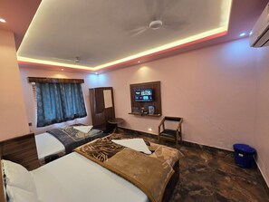 Une chambre d’hôtel avec deux lits, un téléviseur fixé au mur, une armoire et une petite table.