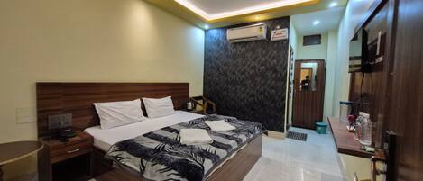 A hotel room with a bed, bedside table, nightstand, and a mirror.