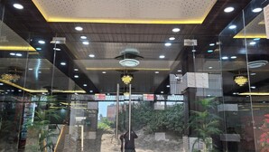 Un interior moderno con entrada de vidrio, una escalera e iluminación empotrada en el techo.