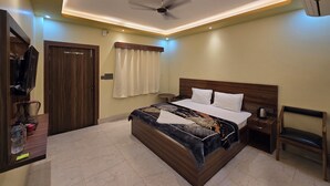 Una habitación de hotel con cama, escritorio, silla, ventilador de techo y aire acondicionado.