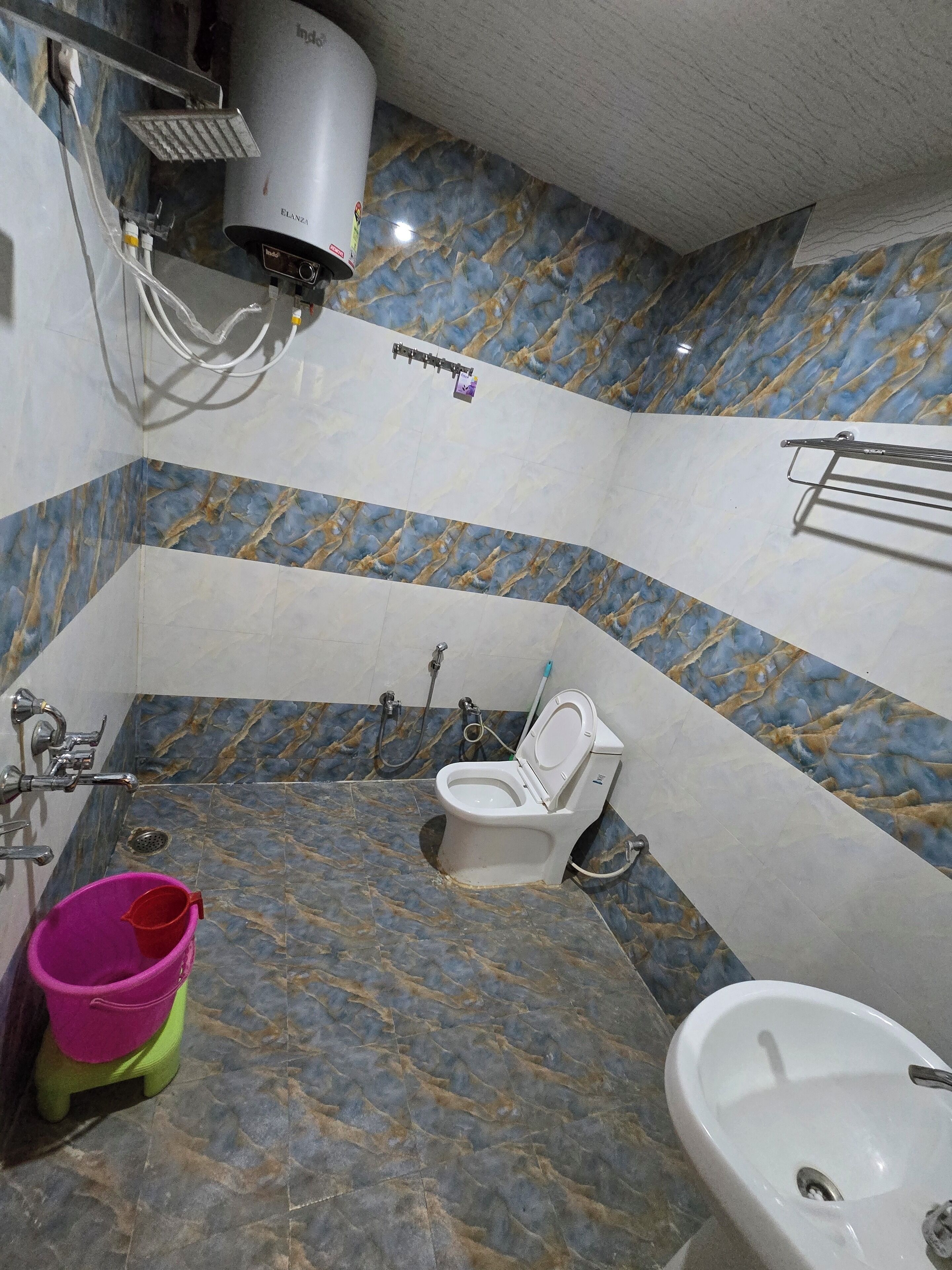 Un baño con suelo de mármol, inodoro, bidé y lavabo.