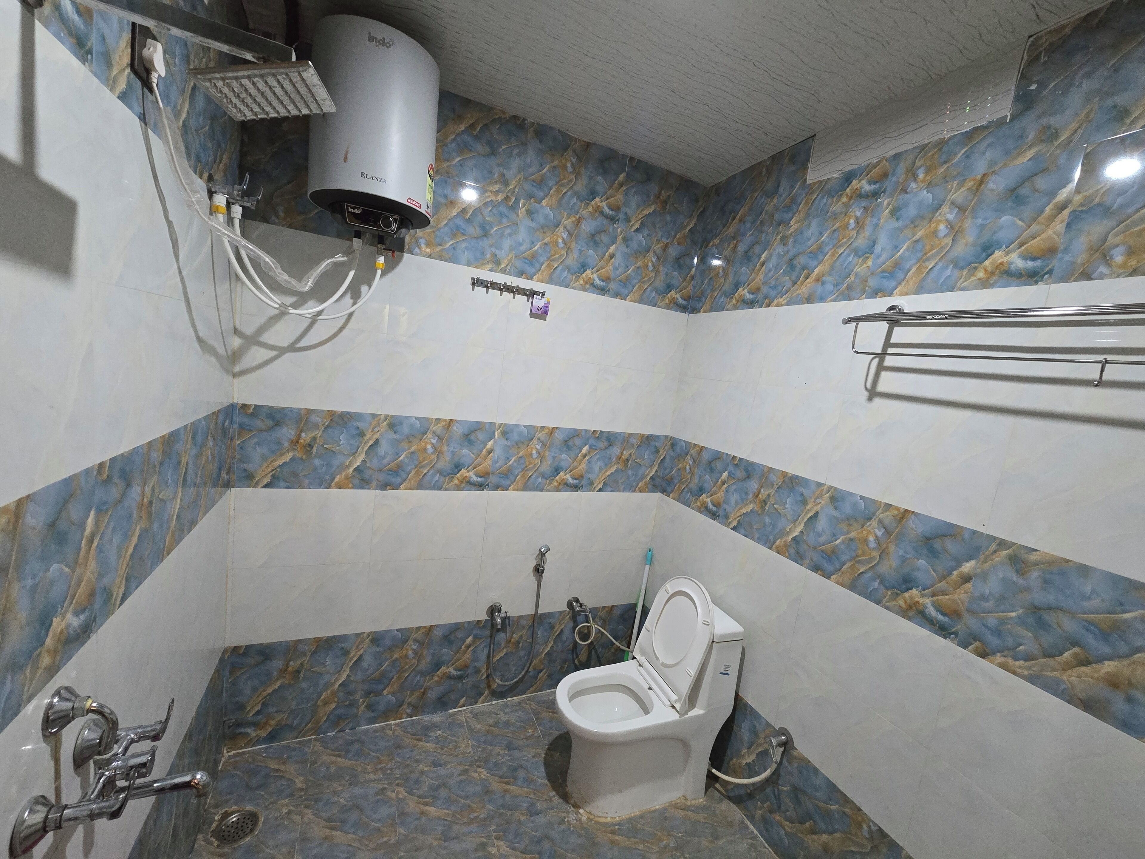 Ein Badezimmer mit Marmorwand, Toilette, Dusche und Handtuchhalter.