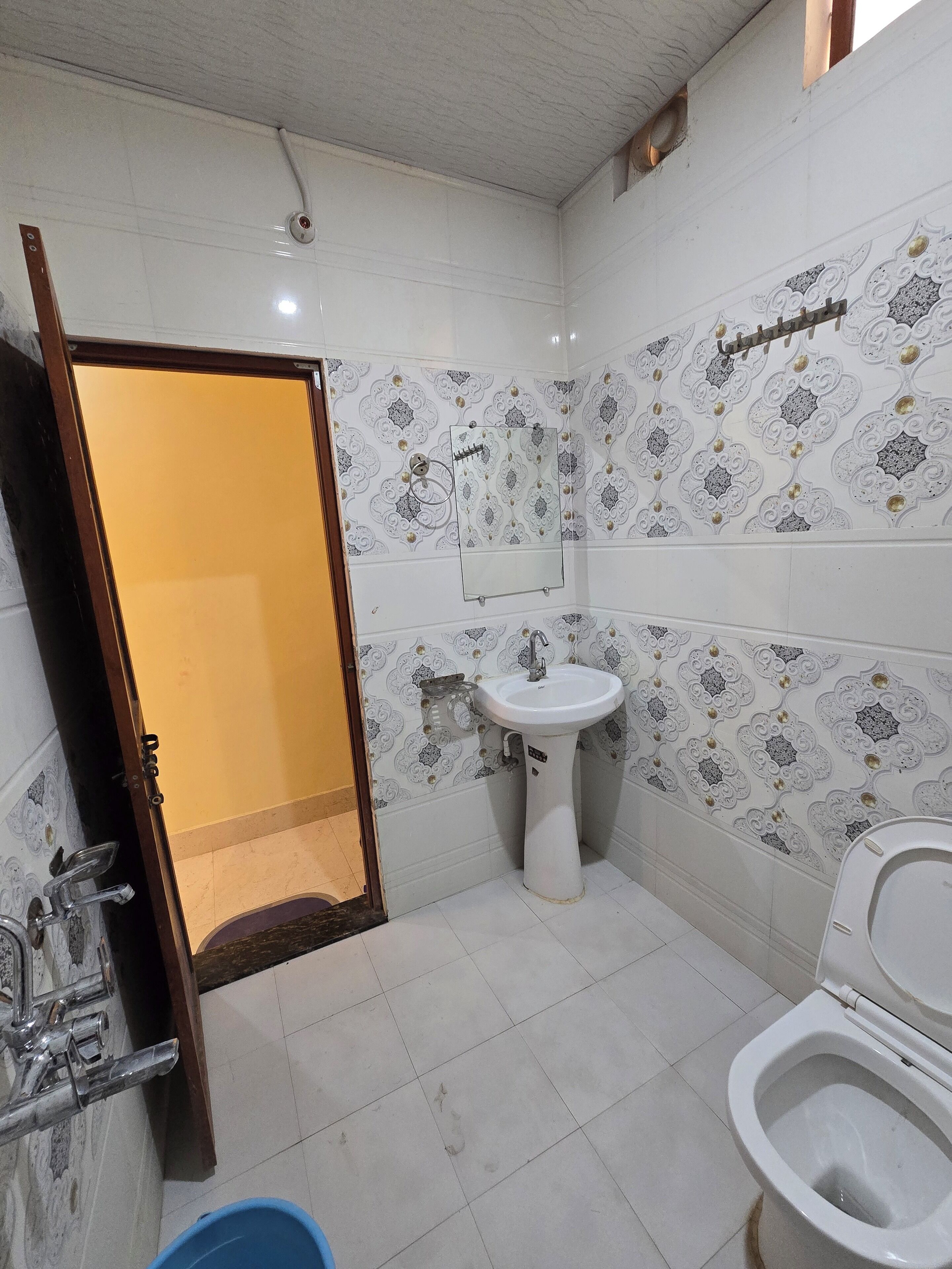 Une salle de bain avec un lavabo blanc, des toilettes et un miroir.