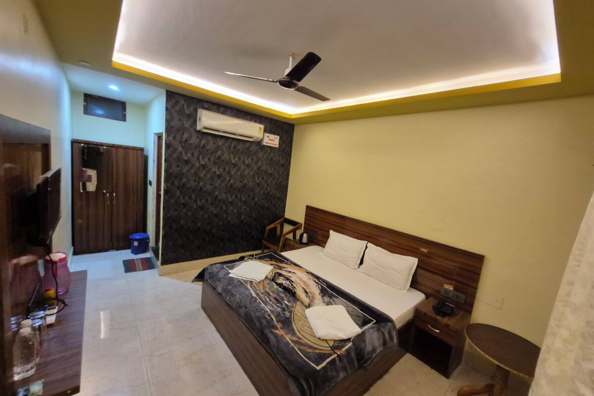 Une chambre d’hôtel moderne équipée d’un lit, d’une table de chevet, d’une commode et d’un ventilateur de plafond.