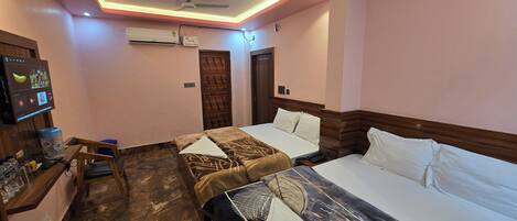 Une chambre d’hôtel avec deux lits, un bureau avec un ordinateur, un appareil de climatisation et un téléviseur fixé au mur.