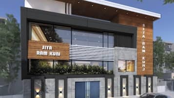 A modern building with a large glass facade, a wooden signboard, and a car parked in front.