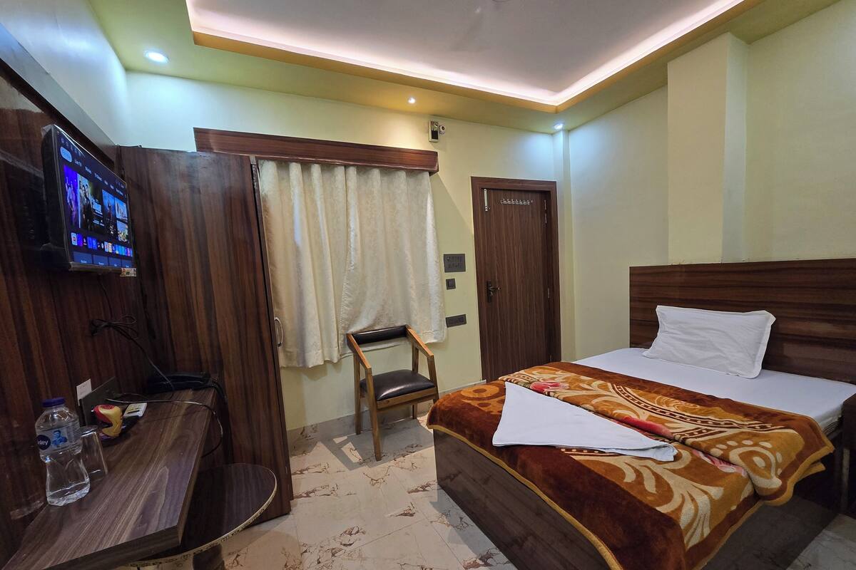 Une chambre d’hôtel avec un lit, un bureau, une chaise, une télévision et une porte.