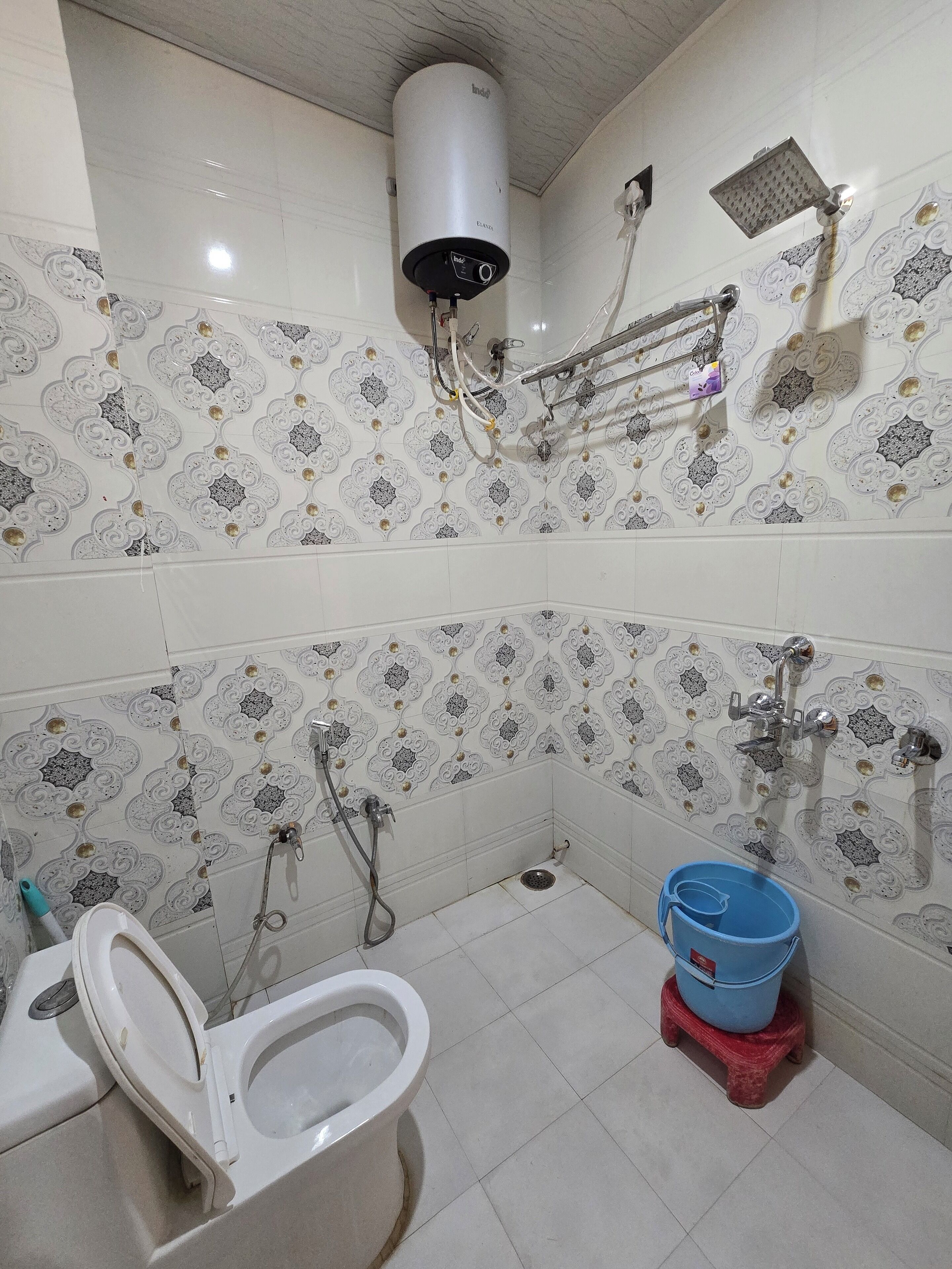 Ein Badezimmer mit Toilette, Dusche und Warmwasserbereiter.