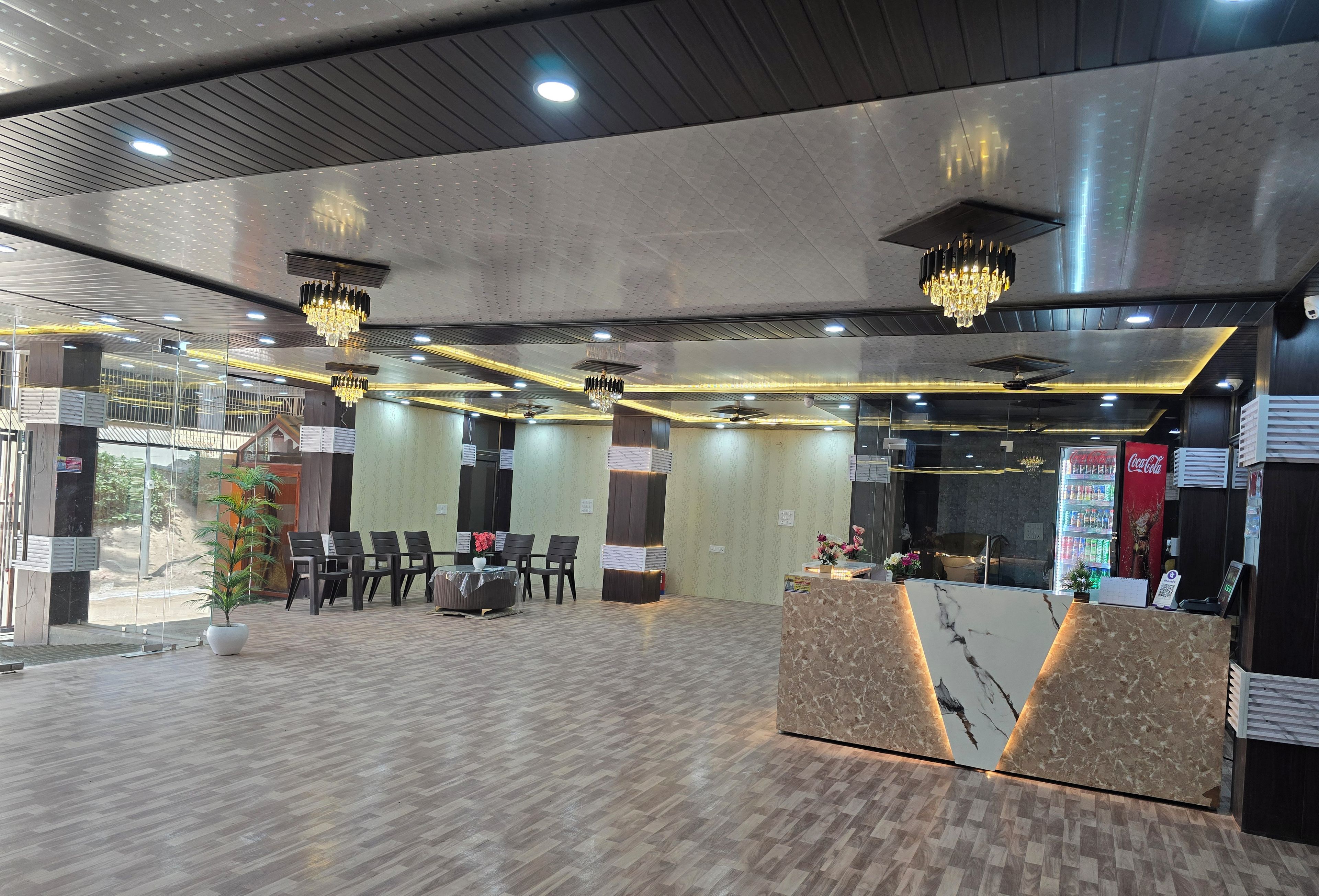 A modern hotel lobby with a reception desk, seating area, and a large Coca-Cola refrigerator.