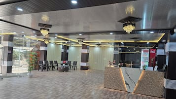 Un moderno vestíbulo de hotel con mostrador de recepción, área de estar y un refrigerador grande de Coca-Cola.
