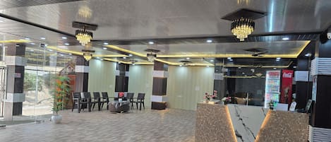 A modern hotel lobby with a reception desk, seating area, and a large Coca-Cola refrigerator.