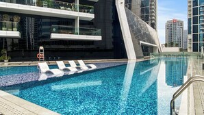 A modern hotel with a rooftop infinity pool, multiple balconies, and a contemporary architectural design. - Waves - Chic High-Floor Studio Retreat with Canal Views (Dubai)