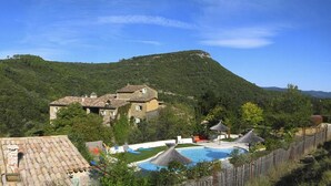 A villa with a swimming pool, surrounded by lush greenery and a mountain backdrop. - Mas Suéjol Gîtes, Gîtes du Mas Suéjol en Cévennes (Anduze)