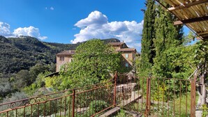 A rustic stone building with a tiled roof, surrounded by lush greenery and hills. - Mas Suéjol Gîtes, Gîtes du Mas Suéjol en Cévennes (Anduze)