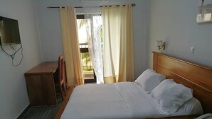 Una habitación de hotel con una cama de madera, un teléfono en la mesita de noche y una mesita de noche pequeña de madera.