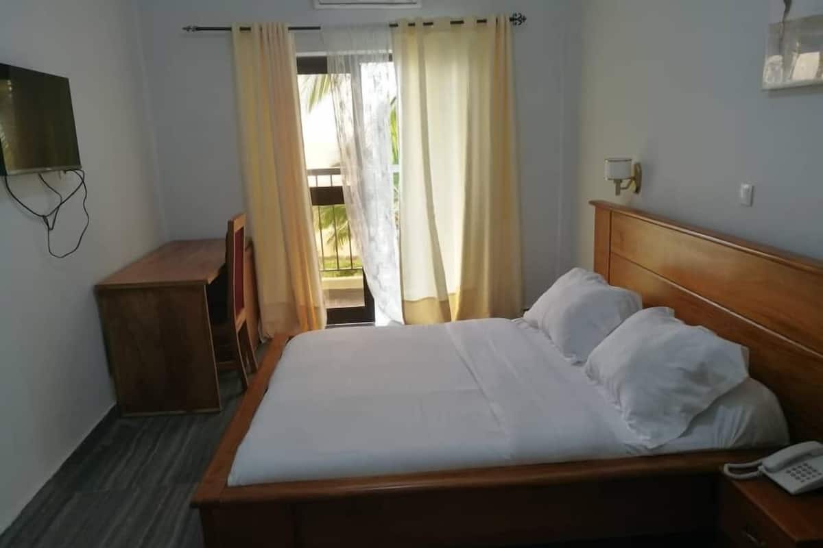 Ein Hotelzimmer mit einem hölzernen Bett, einem Nachttischtelefon und einem kleinen Holz-Nachttisch.