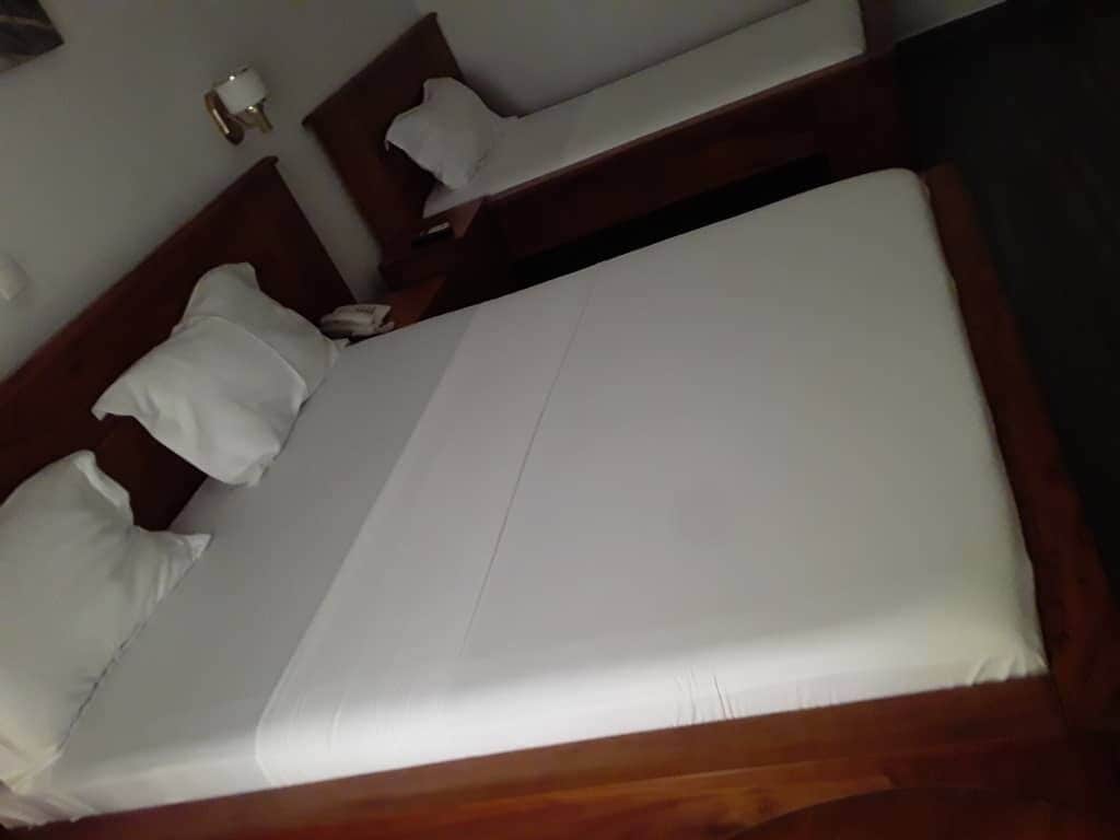A neatly made bed with white linens and a wooden headboard.