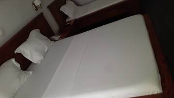 A neatly made bed with white linens and a wooden headboard.