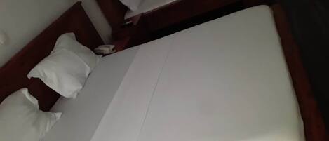Una cama bien hecha con sábanas blancas y un cabecero de madera.