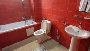 Un baño con un inodoro blanco, un lavabo blanco y una bañera.