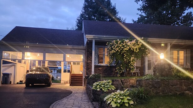 Ein zweigeschossiges Haus mit Garage, Auffahrt und einem Steinweg, der zur Eingangstür führt.