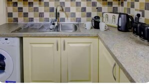 A kitchen with a tiled backsplash, a sink, a coffee maker, and a toaster.