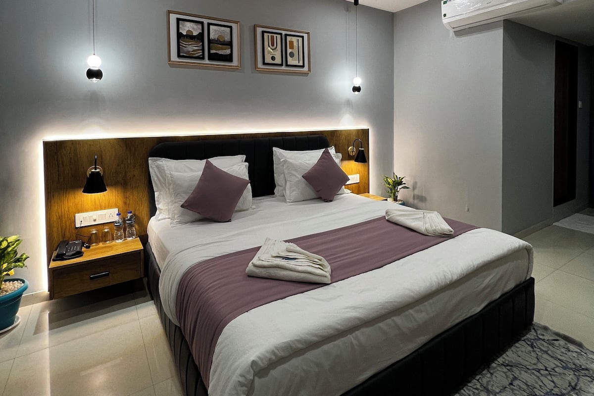Un dormitorio moderno de hotel con una cama grande, lámparas de noche, ventilador de techo y aire acondicionado.