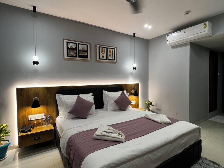 Un dormitorio moderno de hotel con una cama grande, lámparas de noche, ventilador de techo y aire acondicionado.