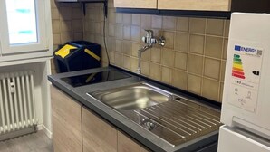 A kitchen with a stainless steel sink, wooden cabinets, a built-in microwave, and a white refrigerator. - Mia Apartment (Lavis)