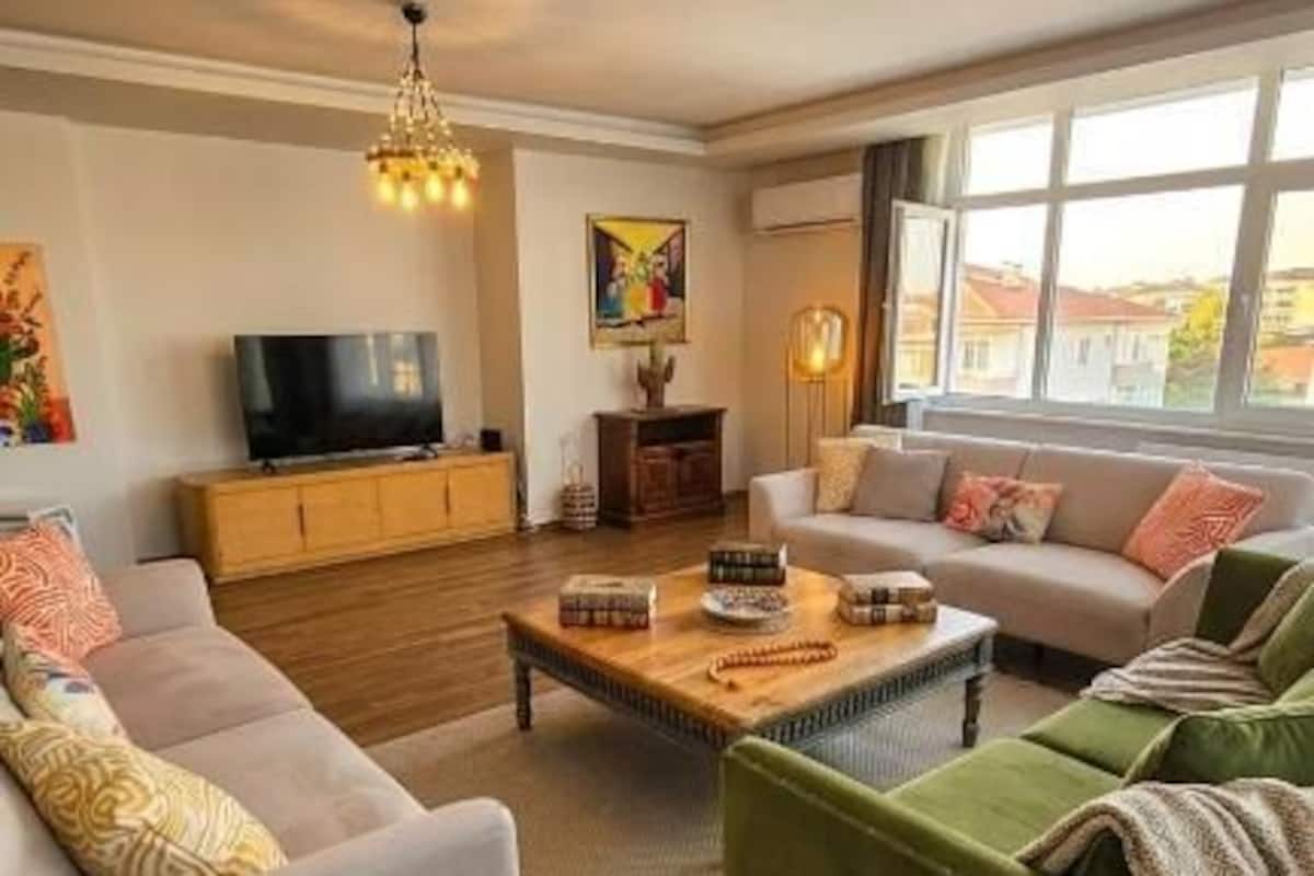 A living room with a sofa, a green armchair, a wooden coffee table, a TV, and a painting on the wall.