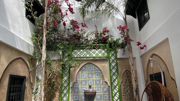 A pool area with a tiled floor, a hanging chair, and a decorative archway. - Privatized Riad in the authentic medina of Marrakech (Marrakech)