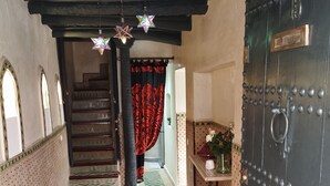 A traditional interior with a staircase, patterned rugs, and a decorative door. - Privatized Riad in the authentic medina of Marrakech (Marrakech)
