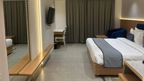 A modern hotel room with a large bed, a desk, a chair, and a TV. - Sapphire Blue (Bhopal)
