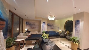 A modern hotel lobby with a reception desk, seating area, and artwork on the walls. - Sapphire Blue (Bhopal)