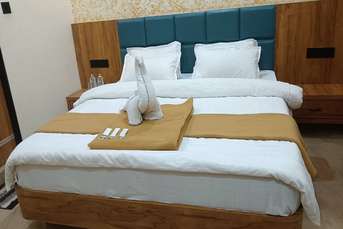 A neatly made bed with white and brown linens, a wooden headboard, and a blue accent wall.
