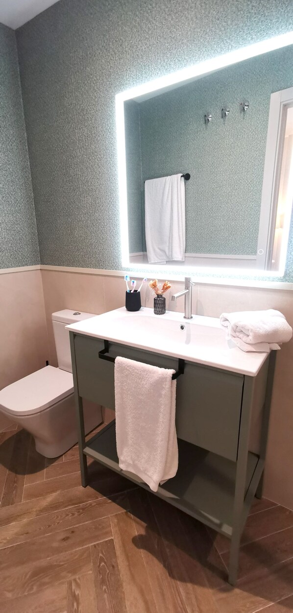 Ein Badezimmer mit einem weißen Waschbecken, einem Spiegel und einem Handtuch an der Wand.