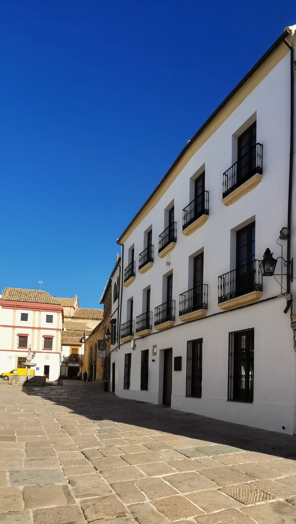 A white building with black balconies and a clear blue sky. - Puerta de la Ribera Suites (Córdoba)