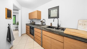 A modern kitchen with wooden cabinets, a black countertop, and a built-in dishwasher. - Charming apartment with AC in living, garden and walking distance to the ocean! (Kralendijk)