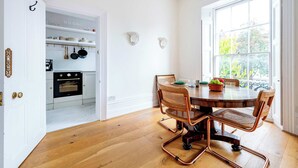 A kitchen with white cabinetry, a wooden dining table, and chairs. - Highlife and Islington - by Out of Office Lifestyle (Greater London)