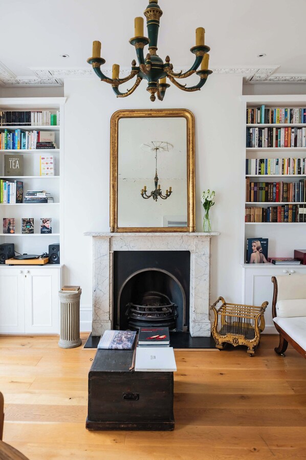A living room with a fireplace, bookshelves, a chandelier, and a vintage armchair.