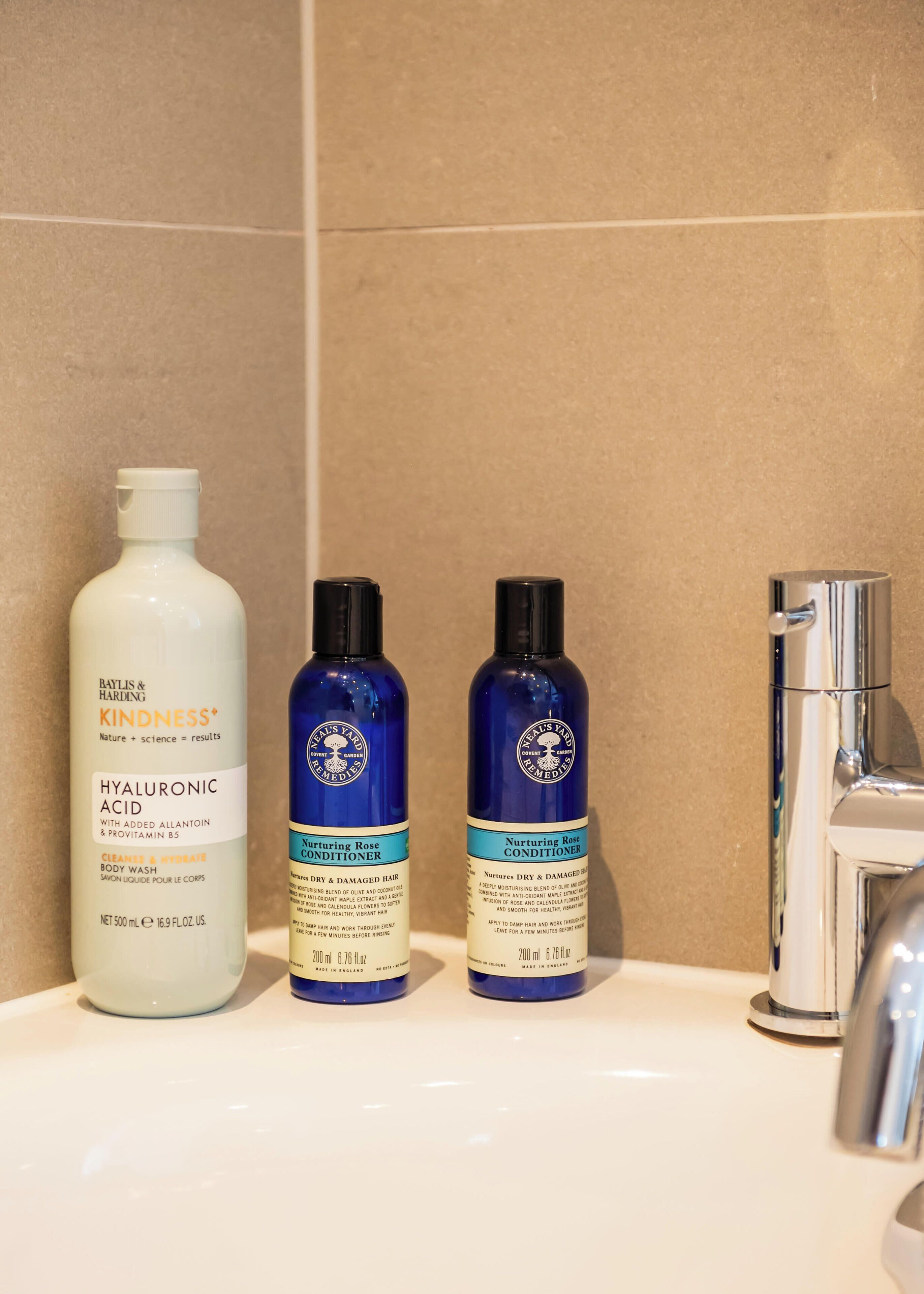 A bathroom sink with three bottles of hair care products.