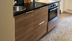 Una cocina moderna con armarios oscuros, encimera negra y pileta de acero inoxidable.