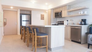 A modern kitchen with a central island, bar stools, a microwave, and a dishwasher. - New Ocean View Beach Front Deluxe Condo! (Jaco)